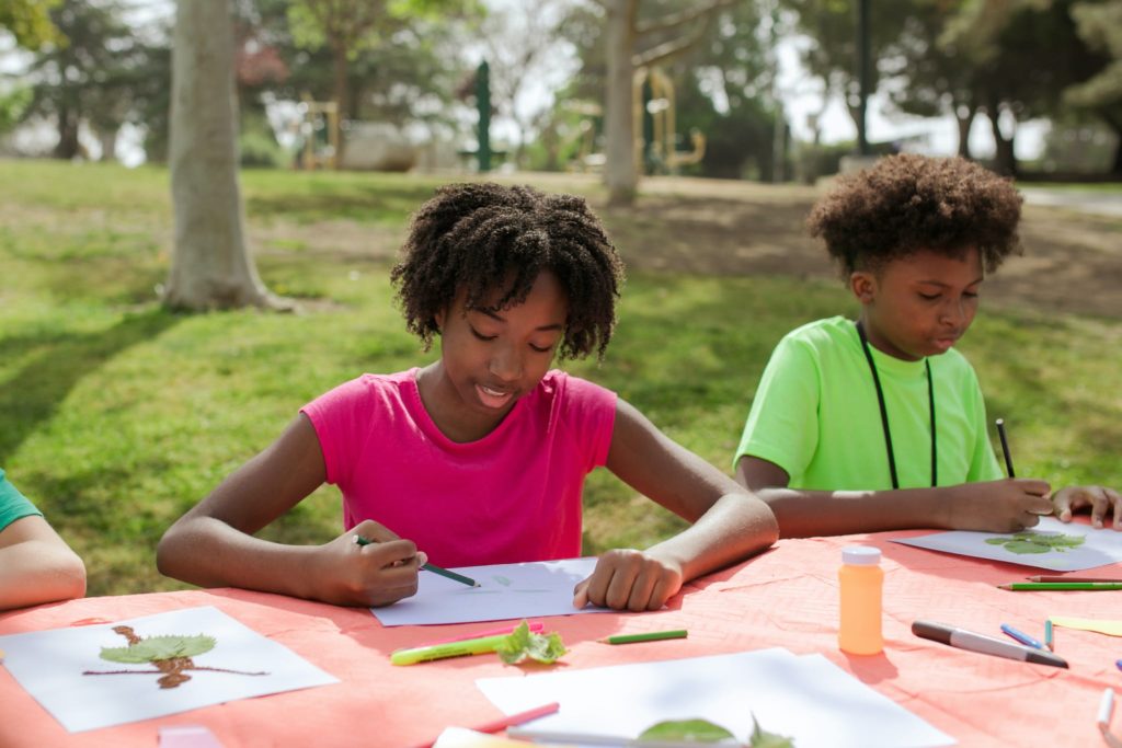 A Young Girl and Boy Writing and Drawing on Papers at the Table