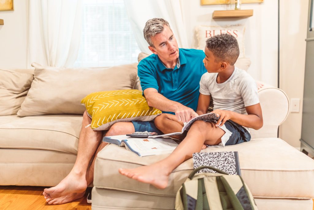 Dad and Son Sitting on a Couch While Reading a Book