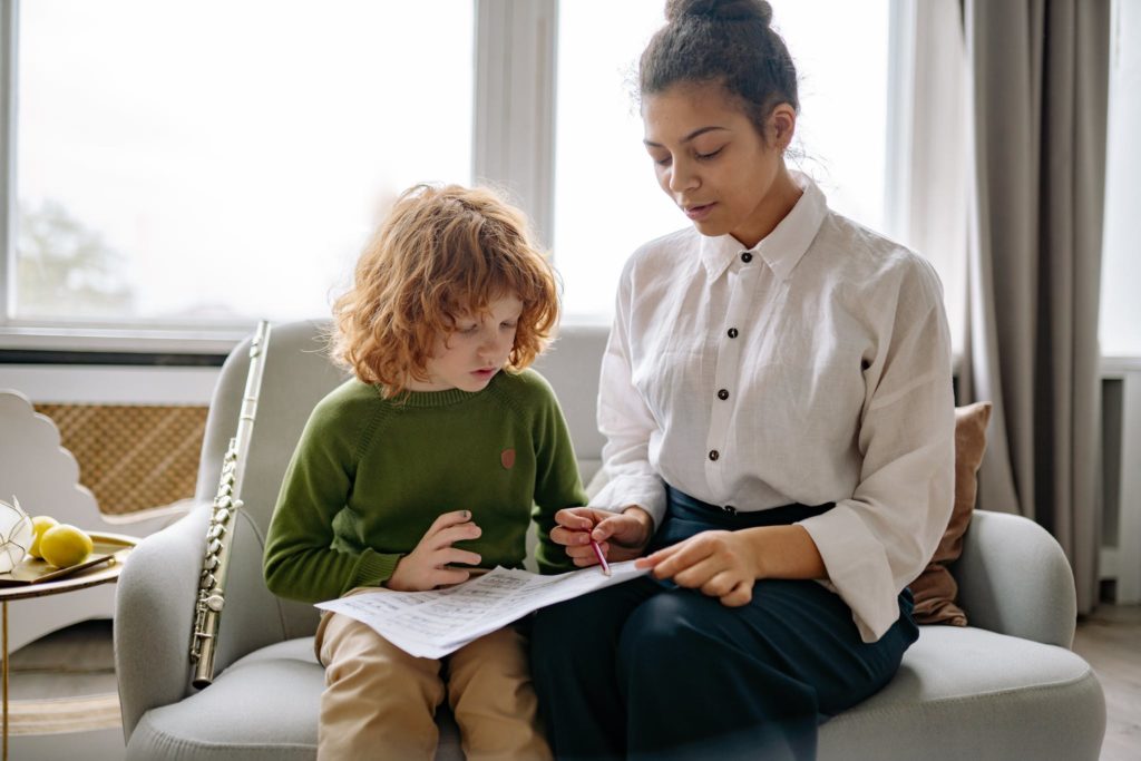 Women in White Button Up Long Sleeve Shirt Sitting Beside a Boy in Green Long Sleeves